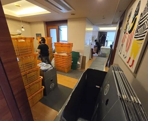 아파트 거실에 포장 상자를 쌓아 두고 이삿짐을 싸는 작업자